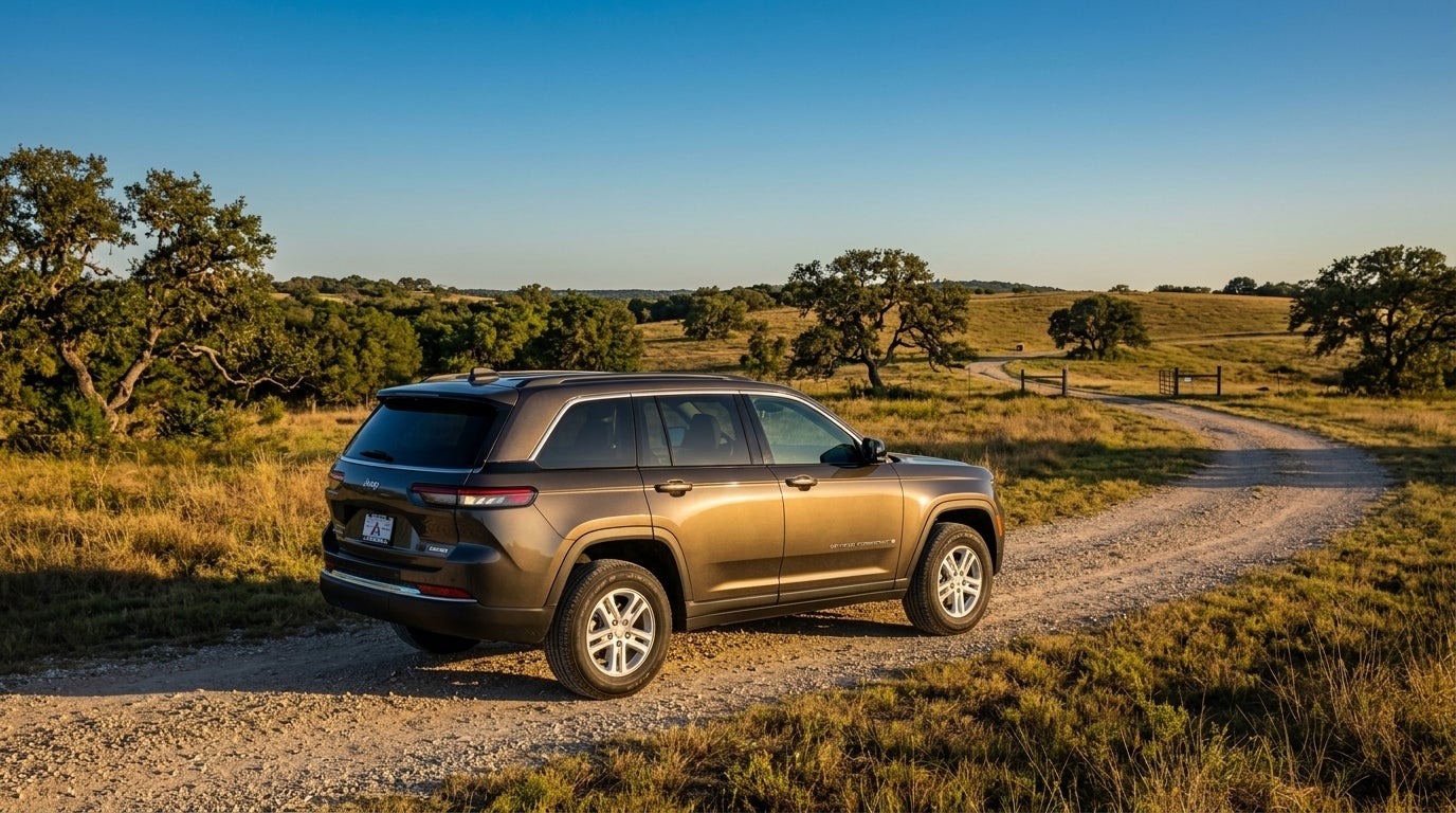 Bronze Jeep Grand Cherokee L parked on a dirt road in a rural landscape during golden hour. (Representative image for illustration purposes only. Actual vehicle may vary based on trim and configuration.)